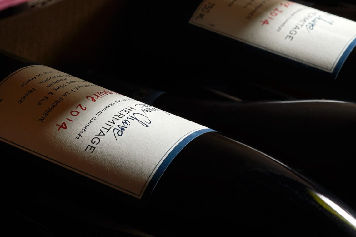 Wine bottles stacked in a cardboard box with visible labels.